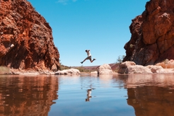 Man jumping over the water at Glen Helen Gorge